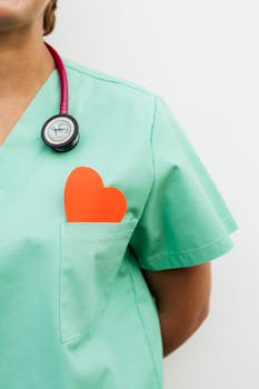 Nurse in pastel green scrubs with stethoscope and paper heart for heart health awareness.